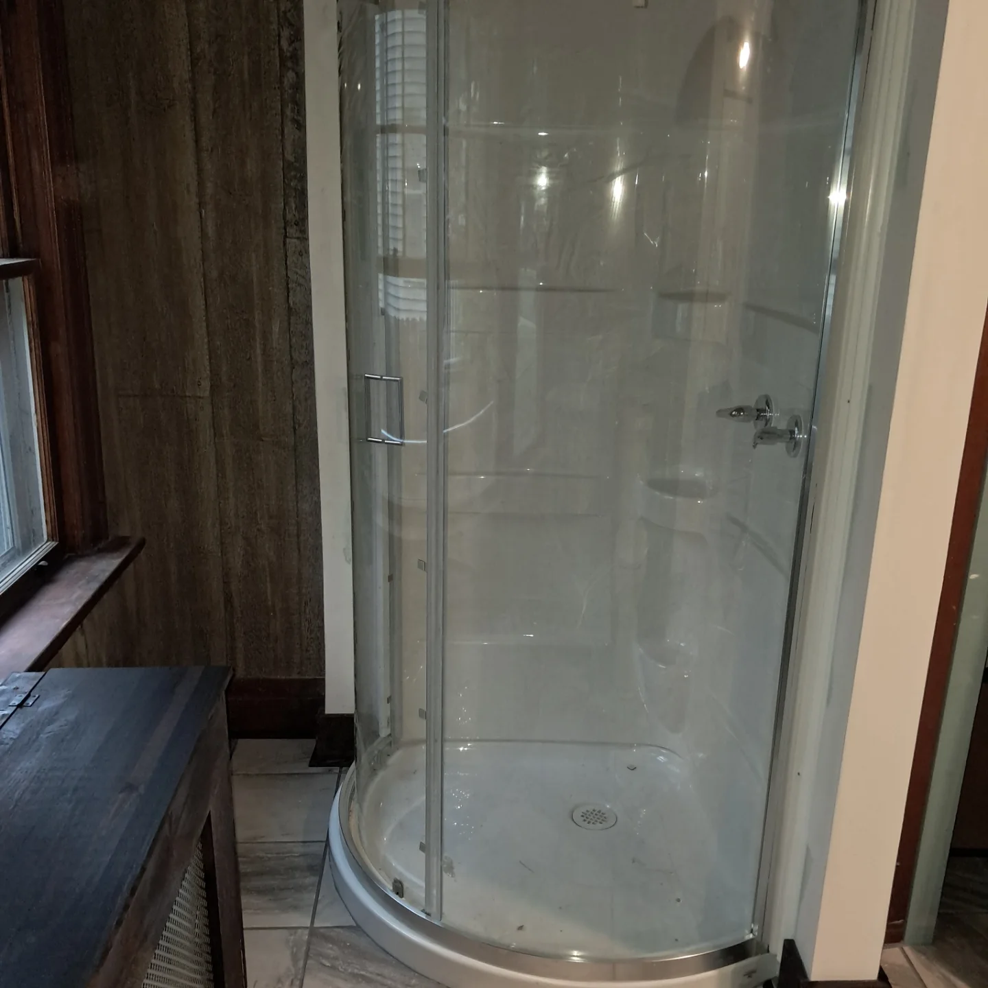 Corner shower enclosure installed in a bathroom with tile flooring