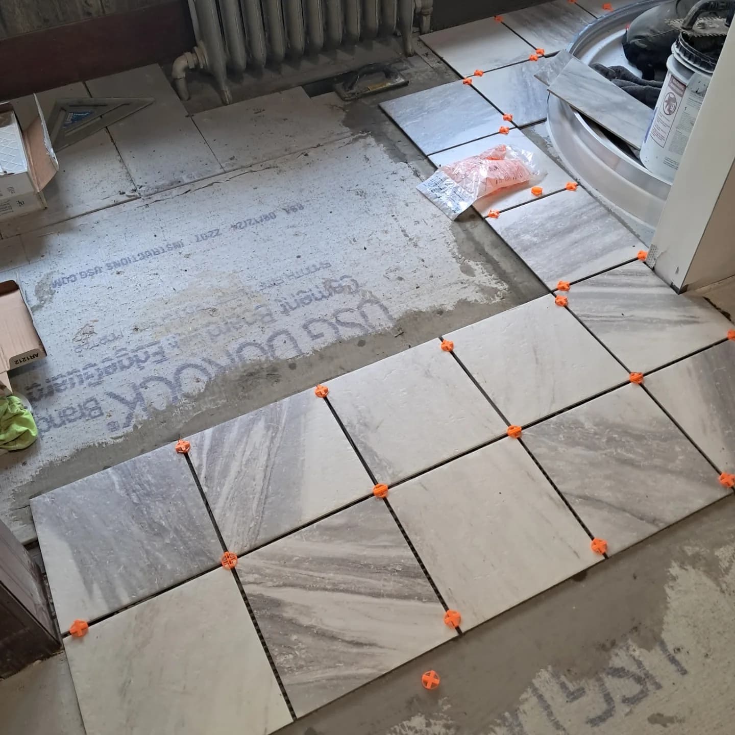 Large-format tile being set with leveling clips
